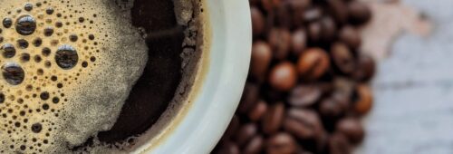 Pyszna kawa bez ekspresu, czarna kawa w filiżance na tle ziaren kawy