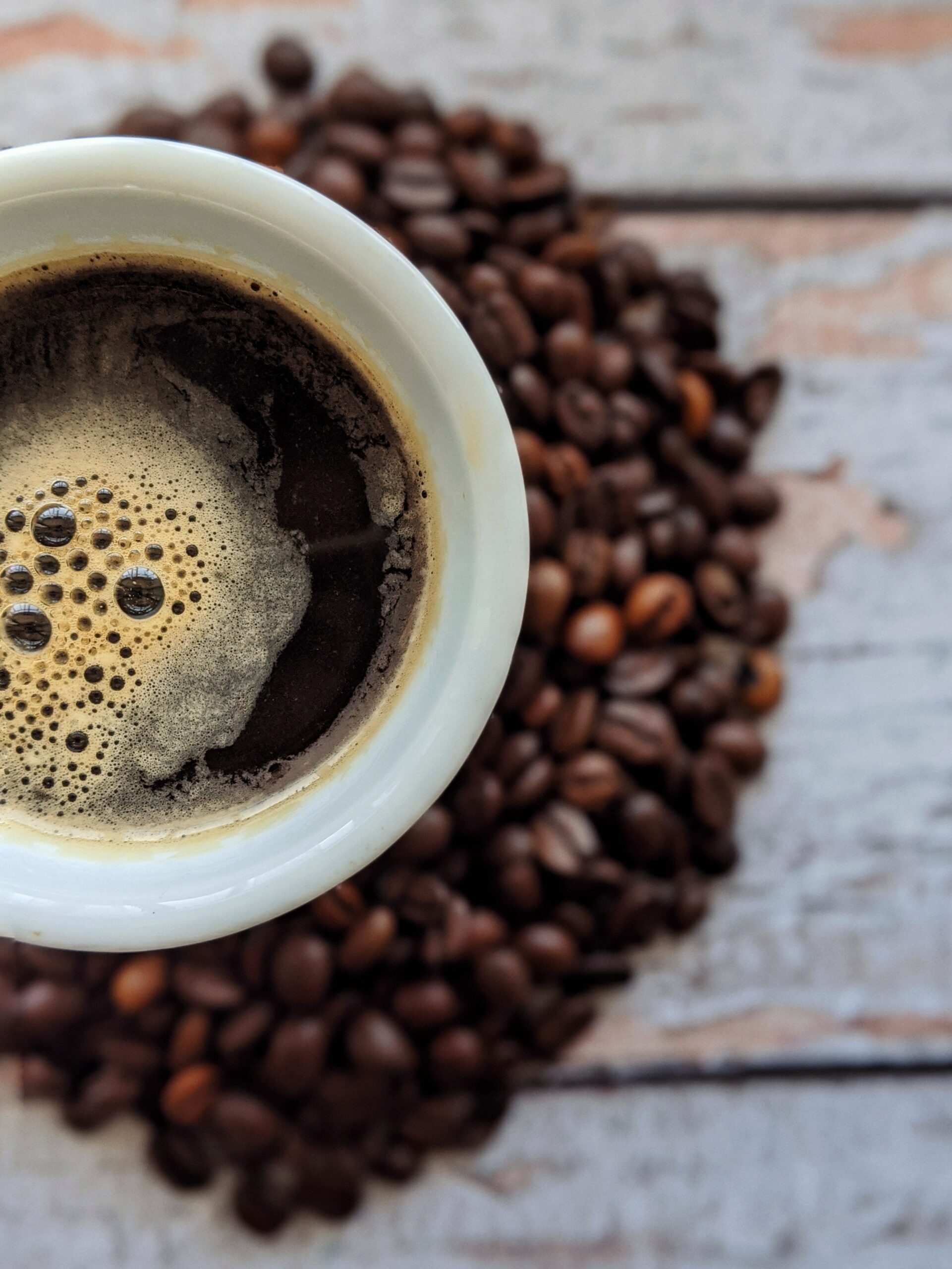 Pyszna kawa bez ekspresu, czarna kawa w filiżance na tle ziaren kawy