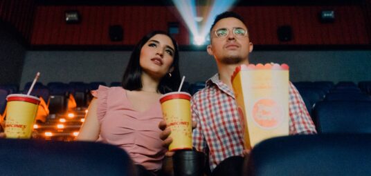 Kino, para siedząca w kinie, trzymająca popcorn i colę